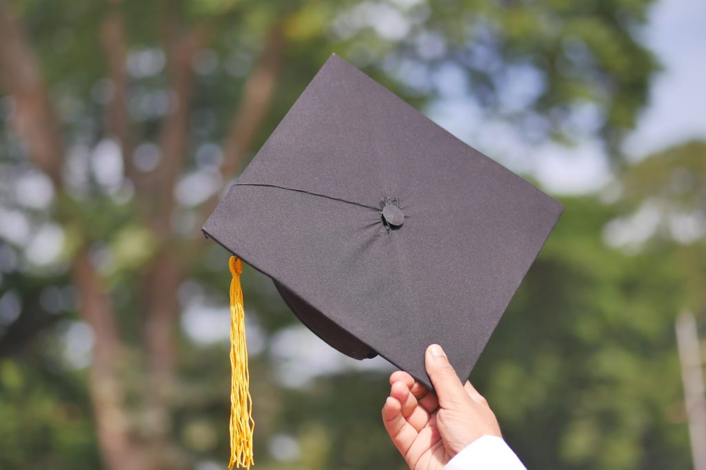 A hand holding a graduation cap, symbolizing achievement and celebration.